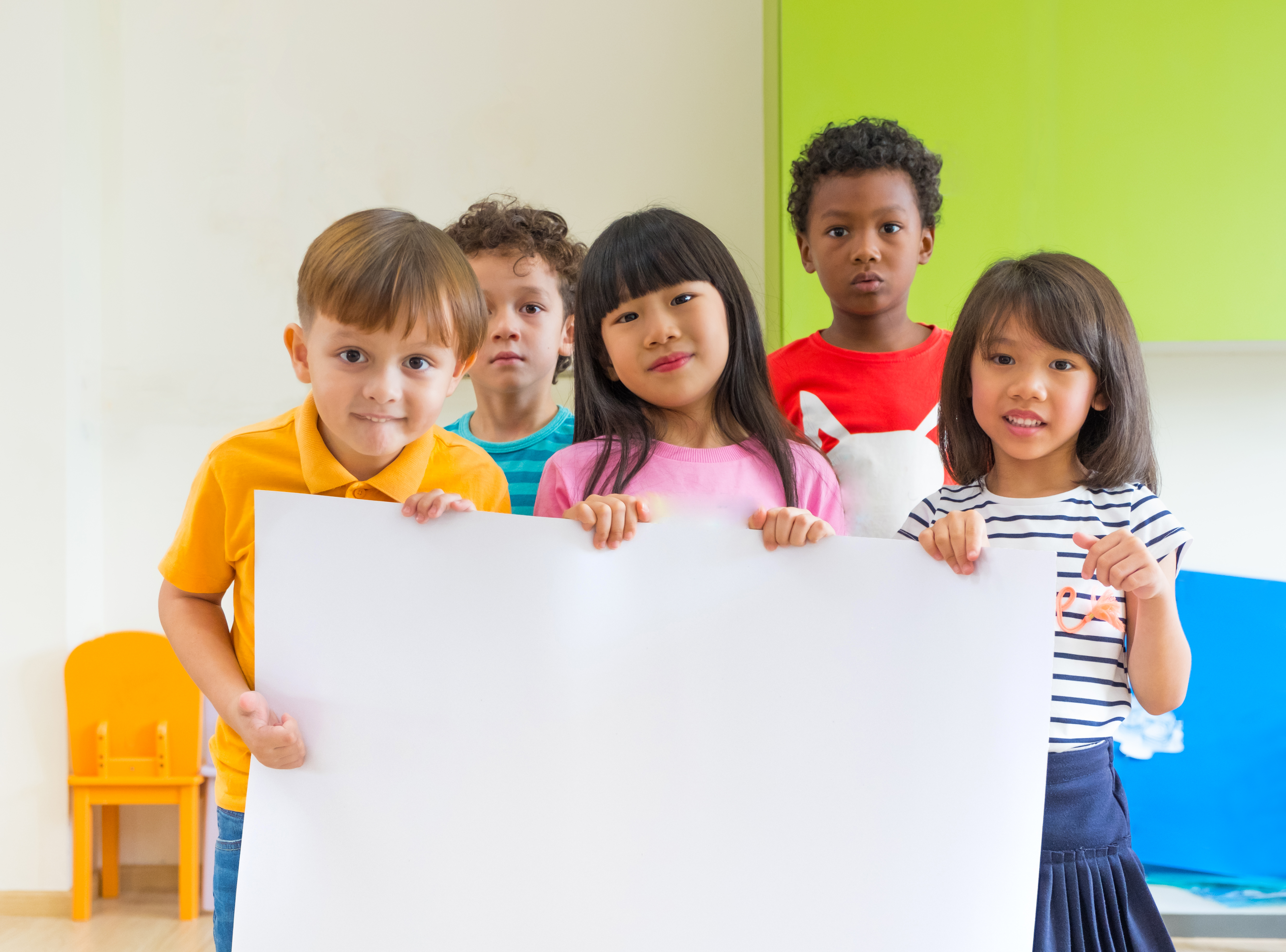 Diversity children holding blank poster in classroom at kindergarten